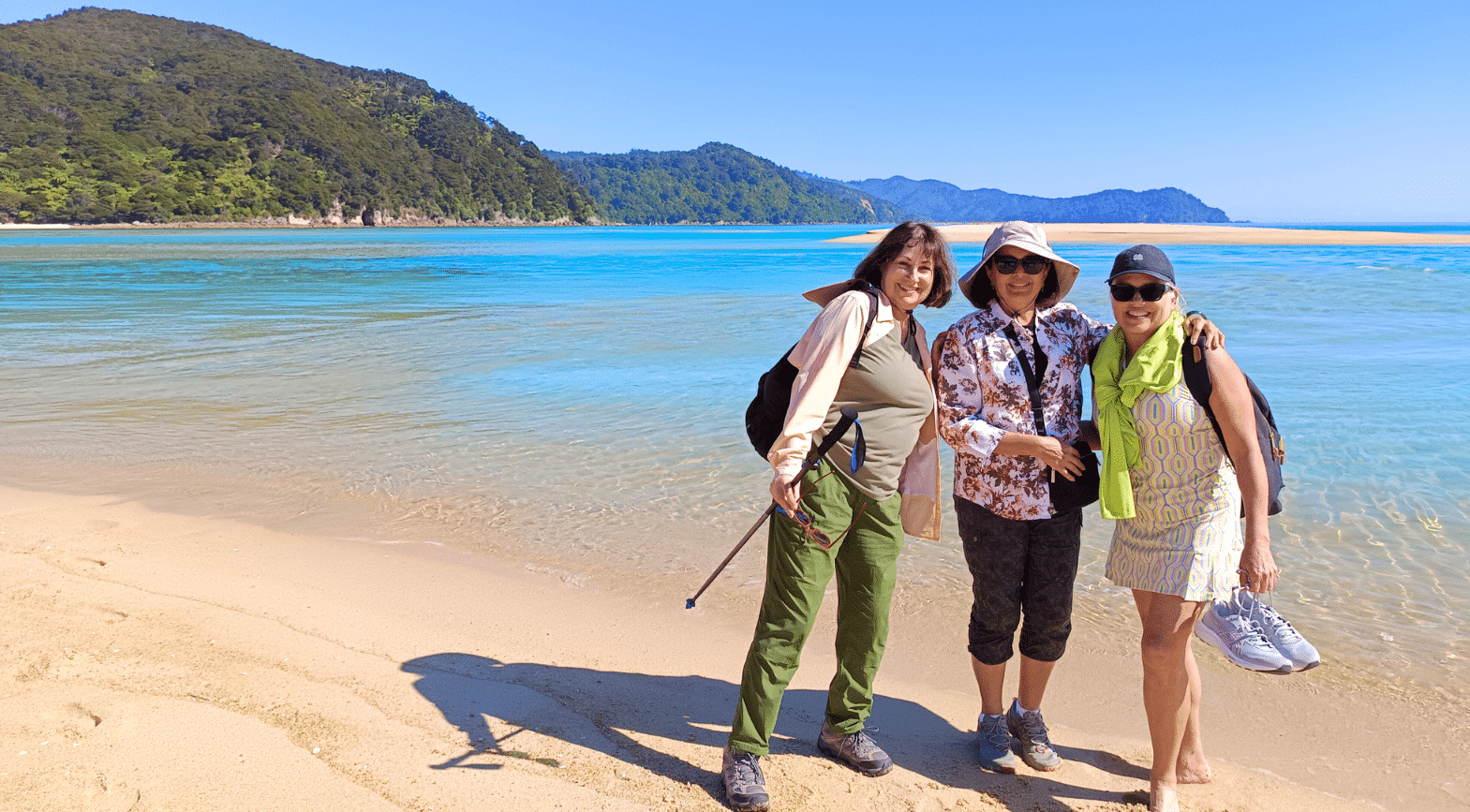 Three female travellers in their 50s, on the beach at Abel Tasman National Park in New Zealand